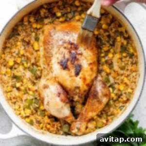 A person is carefully slicing a whole roasted chicken, surrounded by Spanish rice in a skillet.