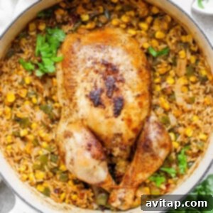 A whole roasted chicken served over a bed of Spanish rice and corn in a skillet, ready to eat.