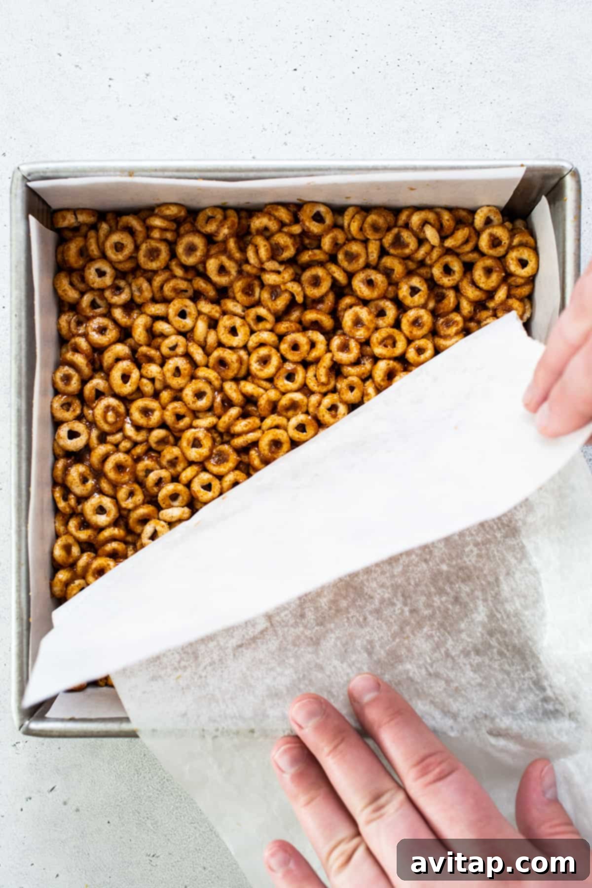 Pumpkin Spice Peanut Butter Crunch Bars 5 A person putting pretzels in a baking pan.