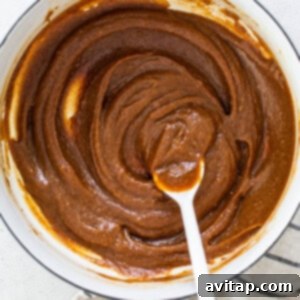 A bowl of peanut butter in a pan with a spoon.