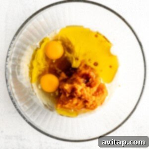 Two eggs in a glass bowl on a white background, ingredients for wet mixture.