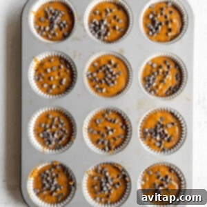 Pumpkin chocolate chip muffins batter in a muffin tin, ready to bake.