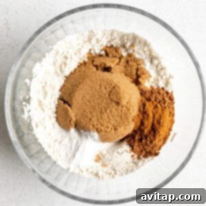 A glass bowl with cinnamon, sugar and flour in it, ready to be mixed.