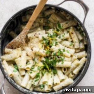 Penne pasta in a skillet with parmesan cheese and parsley, garnished and ready to serve.