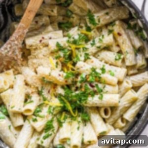 Penne pasta in a pan with parmesan cheese and parsley.