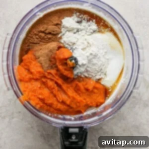 A food processor filled with ingredients for a pumpkin pie.