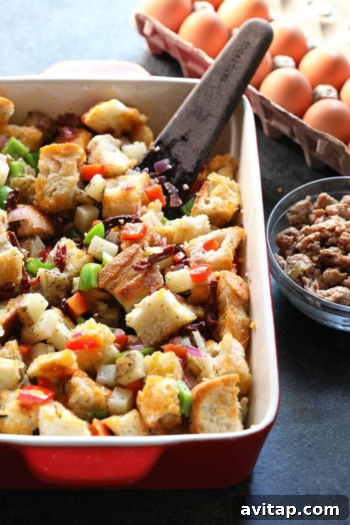 A visual step-by-step of assembling the spicy Italian sausage casserole. Sautéed onions, garlic, and colorful peppers are mixed with browned Italian sausage and chopped sourdough bread in a large baking dish.