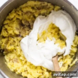 A bowl of batter with whipped cream and a wooden spoon, indicating the final mixing step.