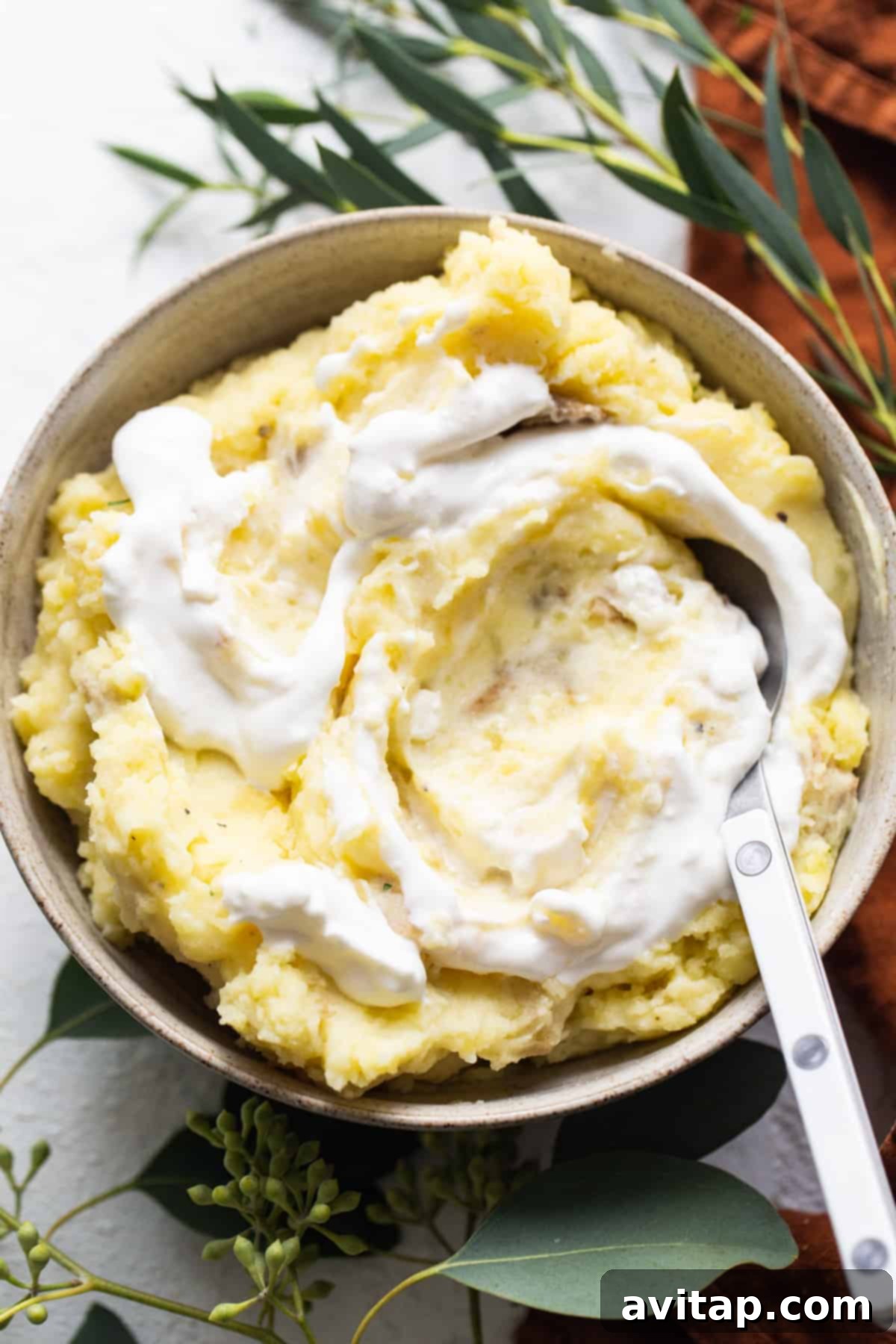 A beautifully presented bowl of whipped cottage cheese mashed potatoes, garnished with fresh herbs and a pat of butter.