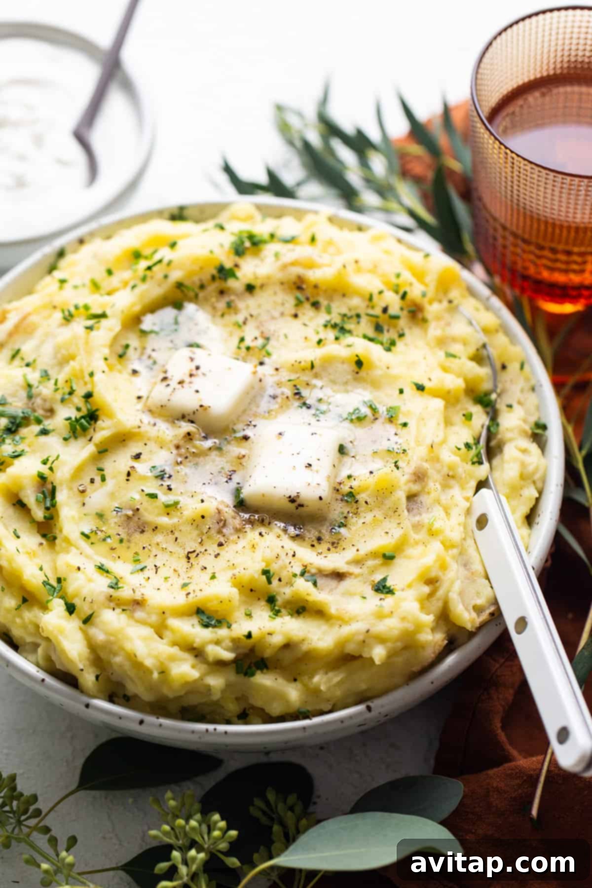 A bowl of mashed potatoes with a swirl of sour cream and fresh herbs, ready to be served.