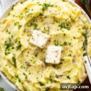 A bowl of mashed potatoes with cheese and herbs, presented appealingly.
