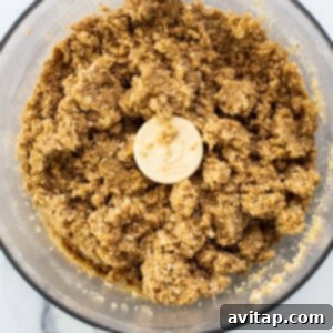 Sun-Kissed Fig & Oat Crumble Squares 10 Wet ingredients being added to the dry oat mixture in a food processor, creating a cohesive crumble.