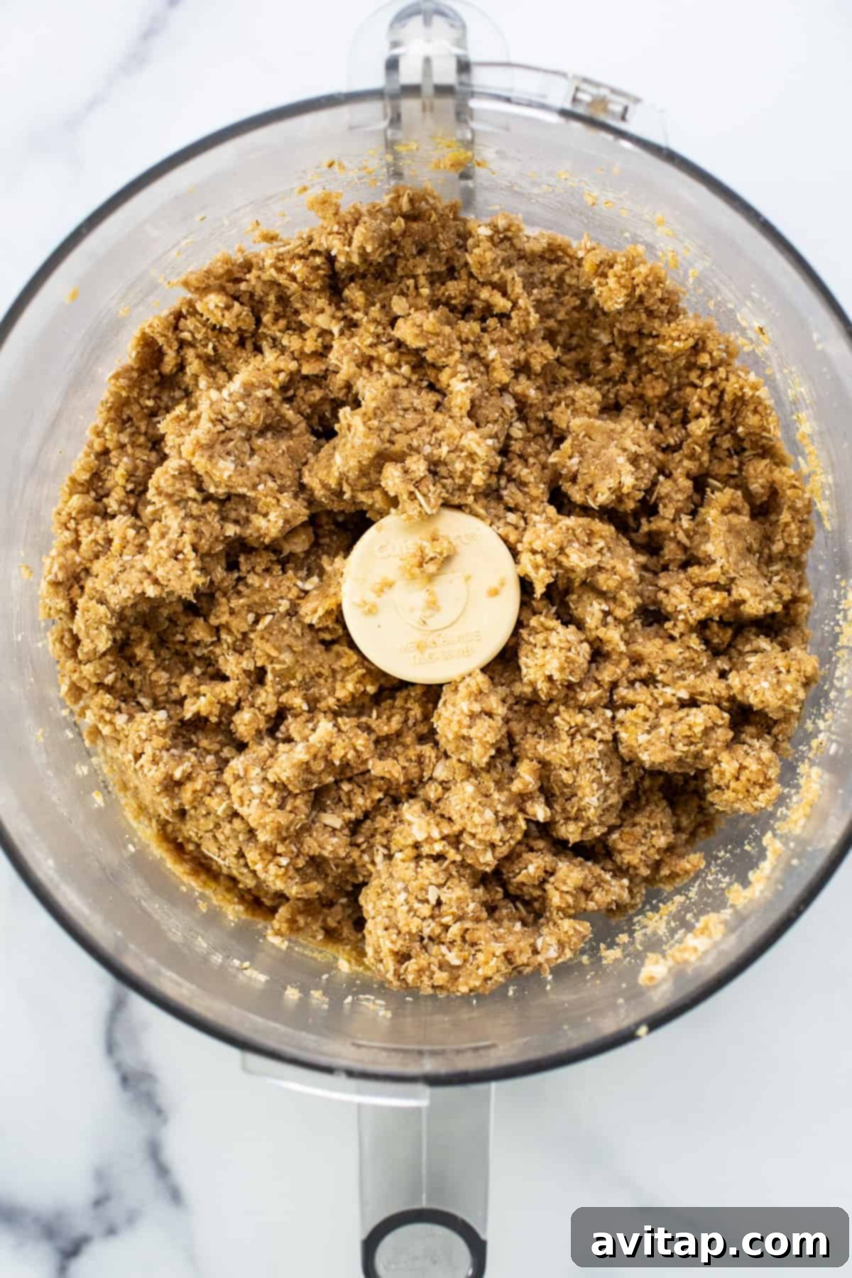 Sun-Kissed Fig & Oat Crumble Squares 4 A food processor bowl filled with oats, flour, and other dry ingredients, ready to be processed for the crumble topping.