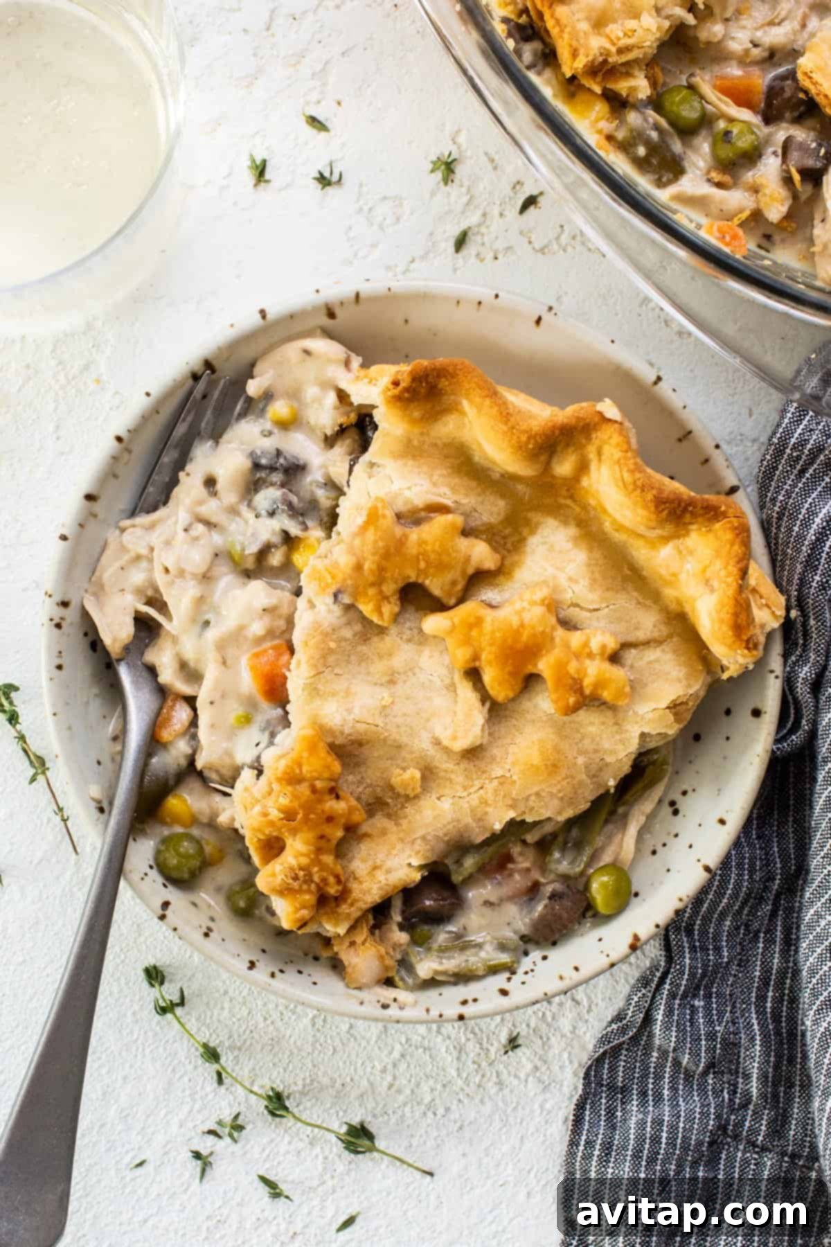 A generous slice of golden-crusted chicken pot pie on a white plate, showcasing the rich filling within.