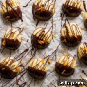 A delightful array of chocolate-covered ricotta cookies, beautifully finished with a sprinkle of fresh orange zest, arranged on parchment paper.