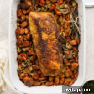 A casserole dish with a beautifully roasted pork tenderloin and golden-brown stuffing, freshly out of the oven.