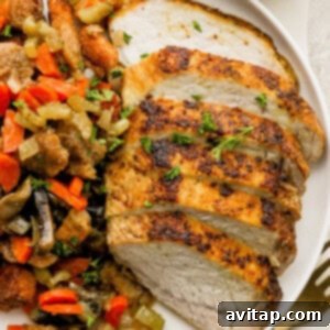 A plate of roasted pork tenderloin and vegetables on a white plate, showcasing the delicious meal.