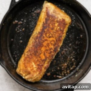 A piece of pork tenderloin searing in a cast iron skillet, achieving a golden-brown crust.