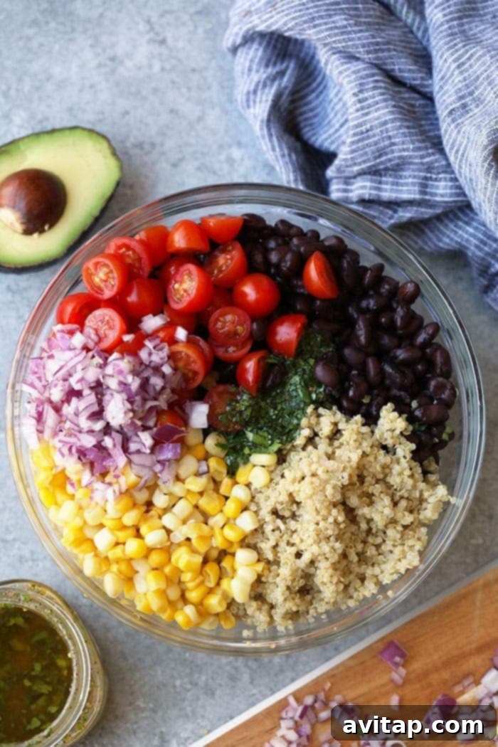 Assorted fresh ingredients for Mexican Quinoa Salad laid out in bowls, including black beans, corn, cherry tomatoes, and red onion.