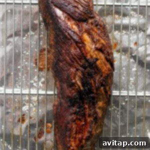 A seared beef tenderloin roast on a cooling rack, freshly removed from the oven and ready for resting.