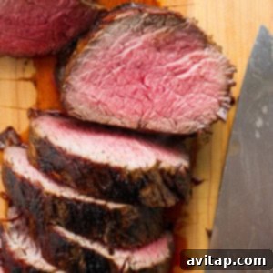 Sliced beef tenderloin on a cutting board, showing its pink, juicy interior, with a carving knife nearby.
