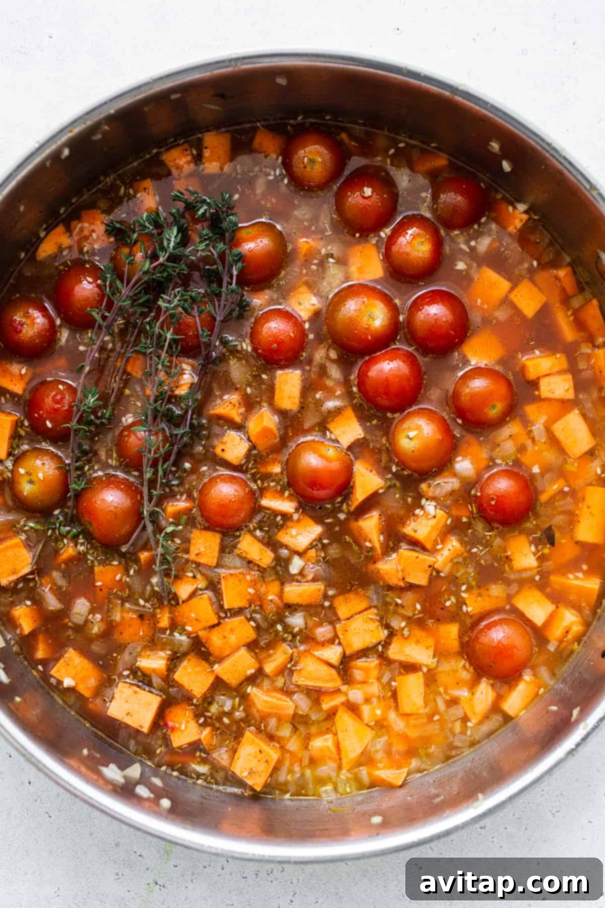 A pan filled with tomatoes and a sprig of thyme.