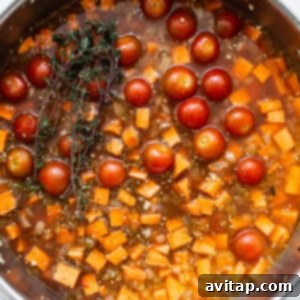 A pan filled with tomatoes and a sprig of thyme.
