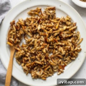 Roasted peanuts on a white plate with a wooden spoon.