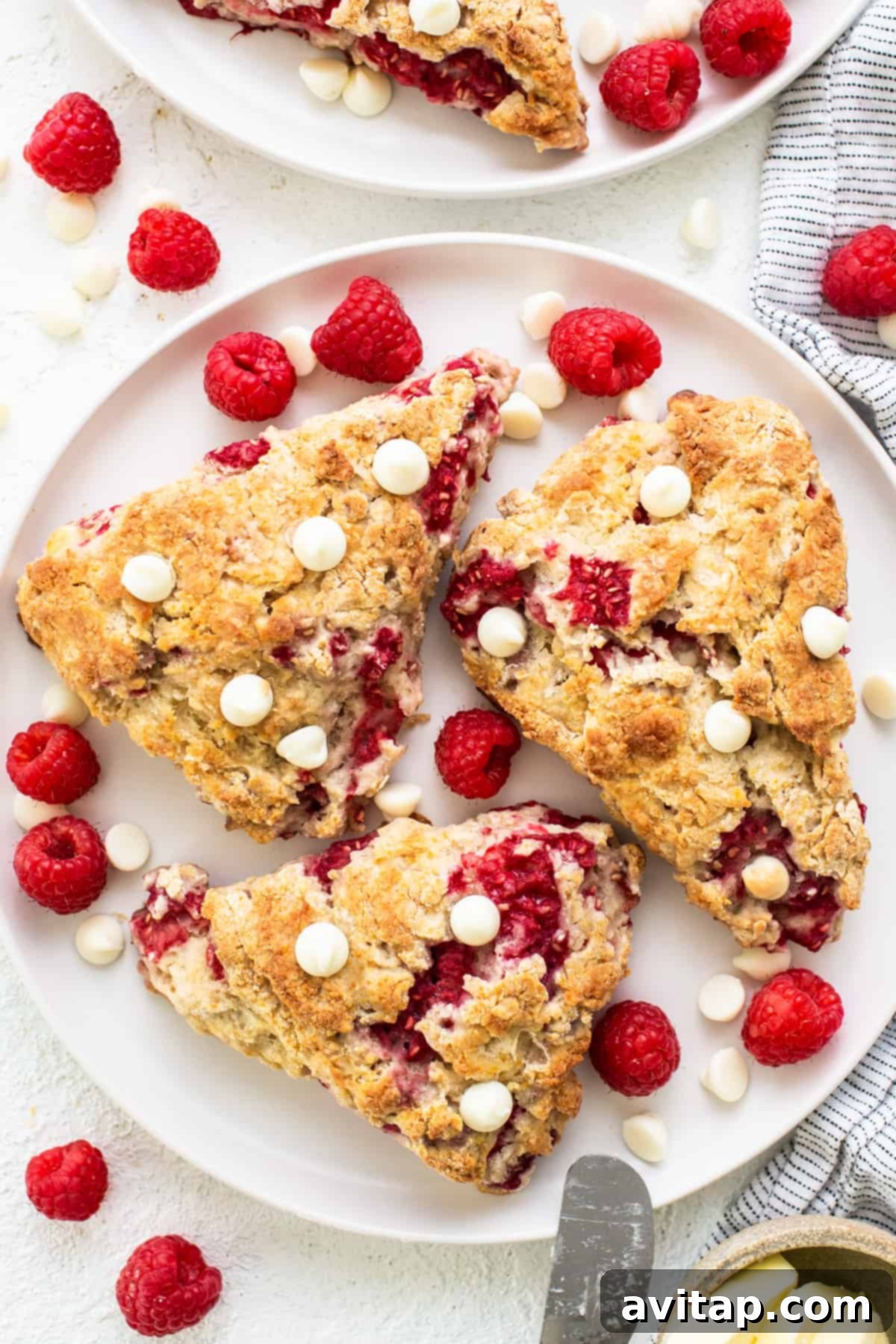Freshly baked white chocolate raspberry scones on a pristine white plate, ready to be enjoyed.