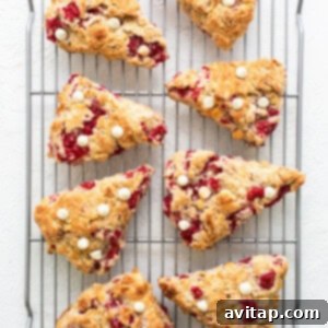 Freshly baked cranberry scones cooling on a wire rack after being removed from the oven.