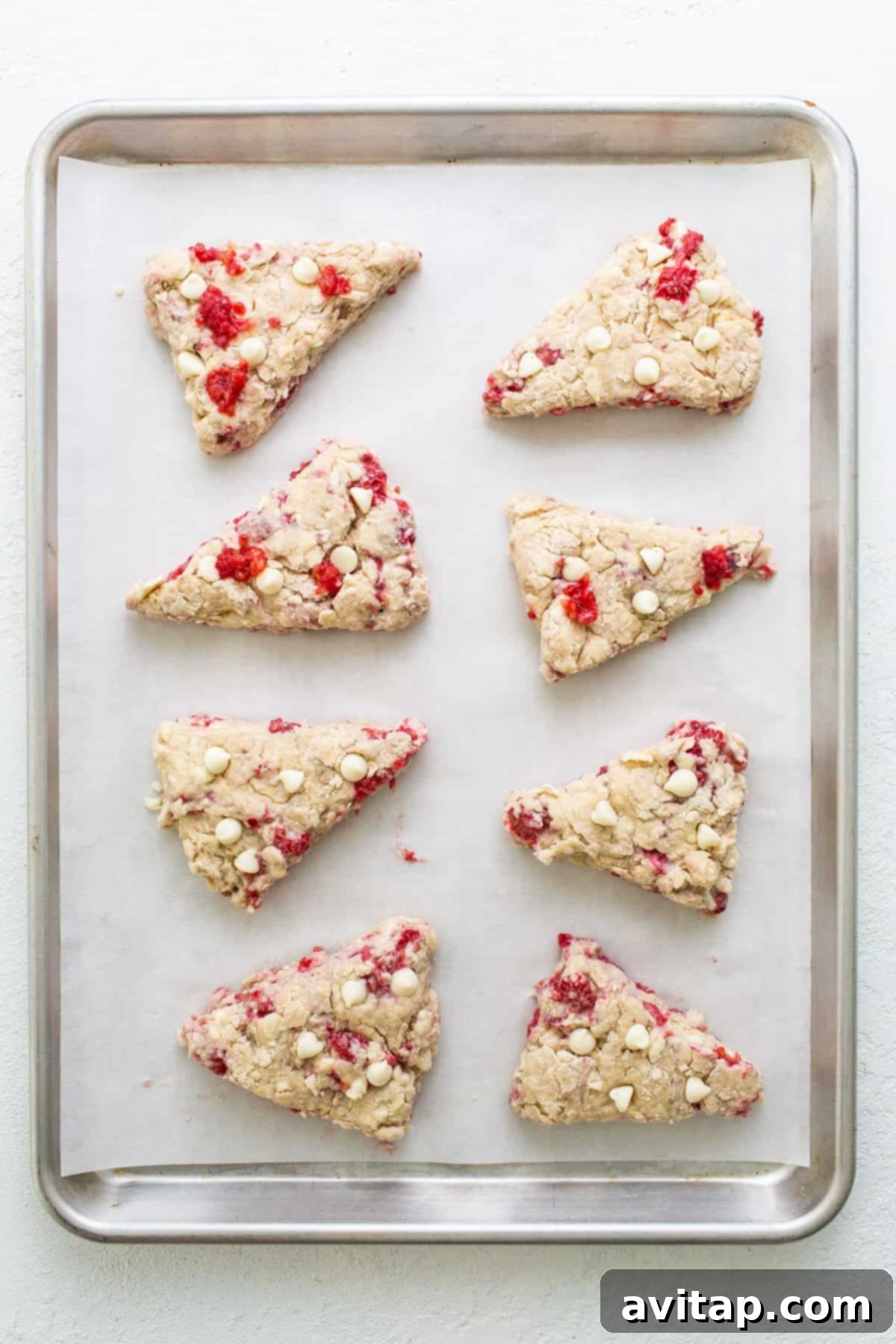 A tray of cranberry almond scones, freshly baked and golden-brown, cooling on a baking sheet.