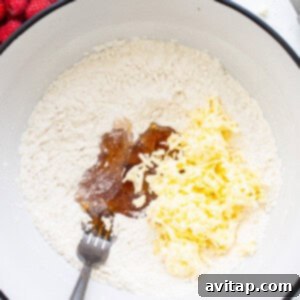 A bowl filled with flour, grated butter, and honey, being mixed to form a scone dough.