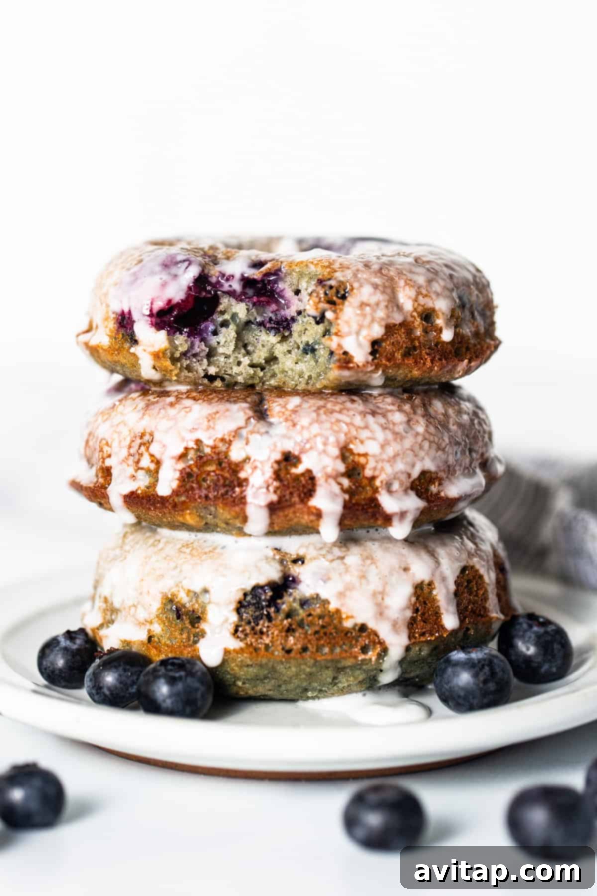 A stack of perfectly glazed blueberry protein donuts on a white plate, ready to be enjoyed.