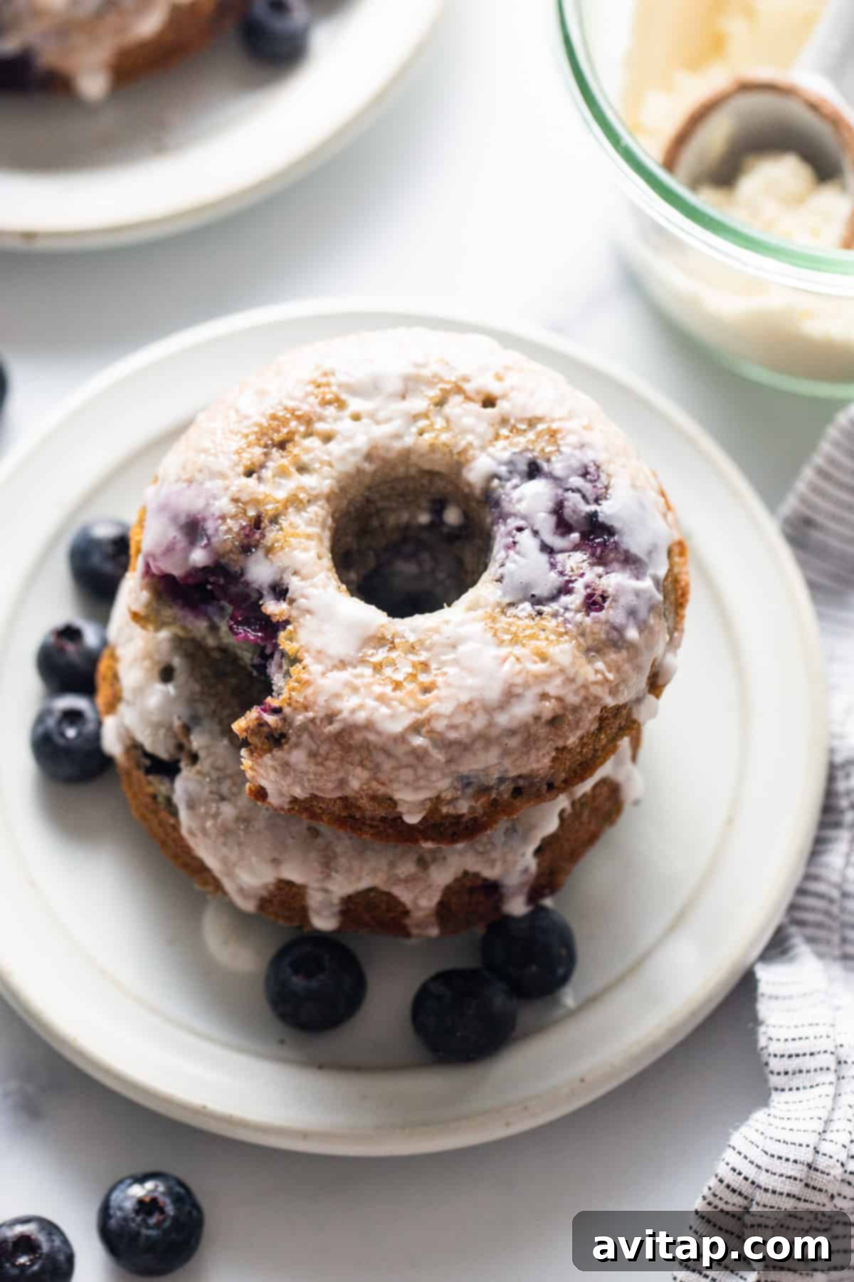 A stack of blueberry donuts on a plate, ready to be served.