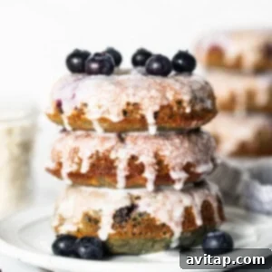 A stack of blueberry glazed donuts on a plate, ready to be enjoyed.