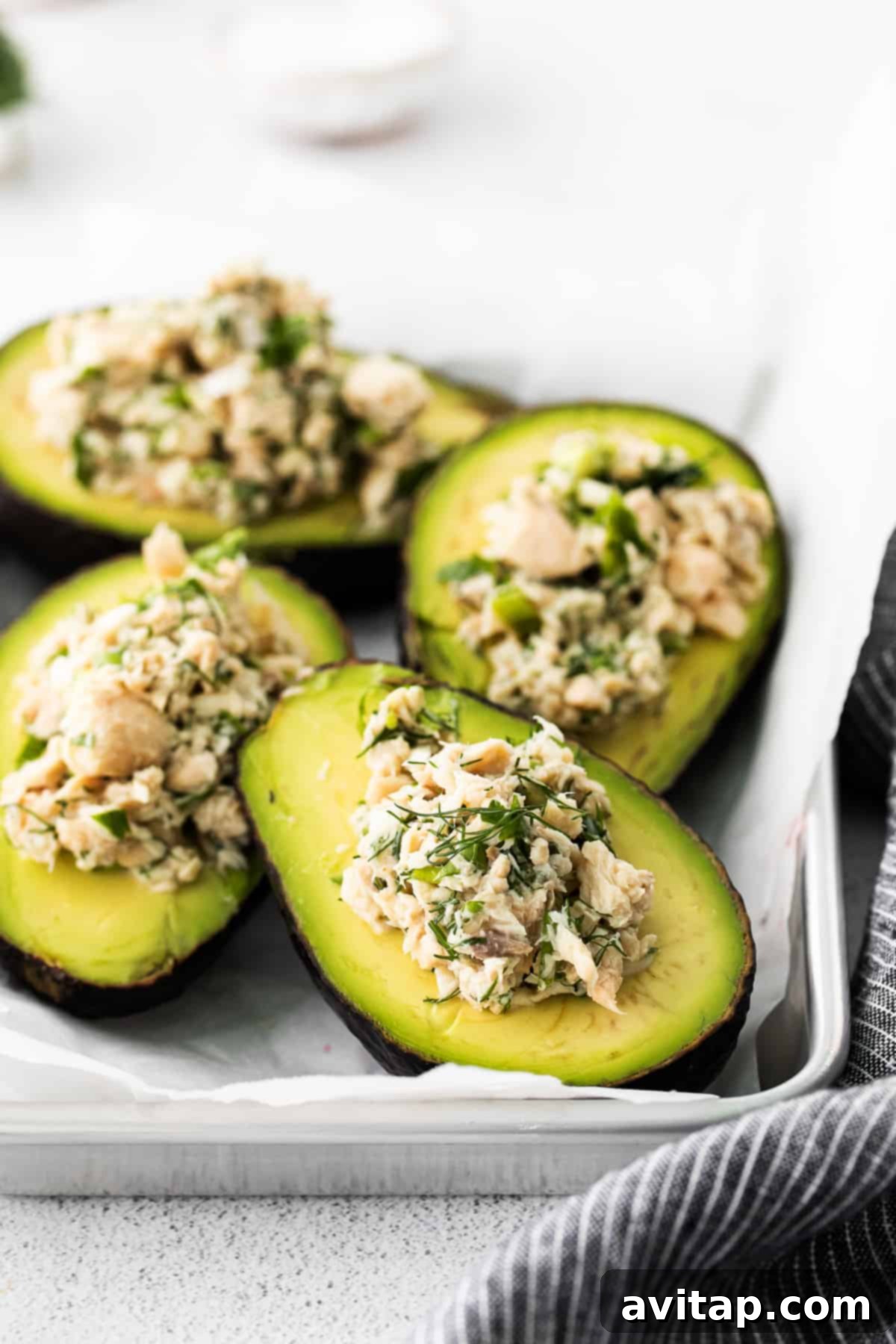Two beautifully arranged stuffed avocado boats, generously filled with salmon salad, resting on a white plate. The vibrant colors highlight the freshness of the ingredients.