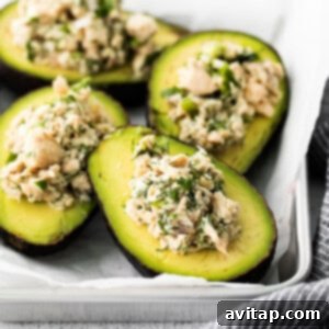 Close-up shot of perfectly stuffed avocados, filled with a rich tuna and herb salad, artfully arranged on a rustic baking sheet, ready to be served.