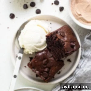 A plate of chocolate brownies with ice cream and whipped cream.