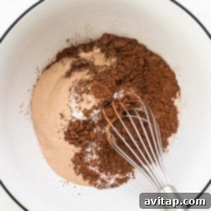 A bowl with cocoa powder and a whisk.