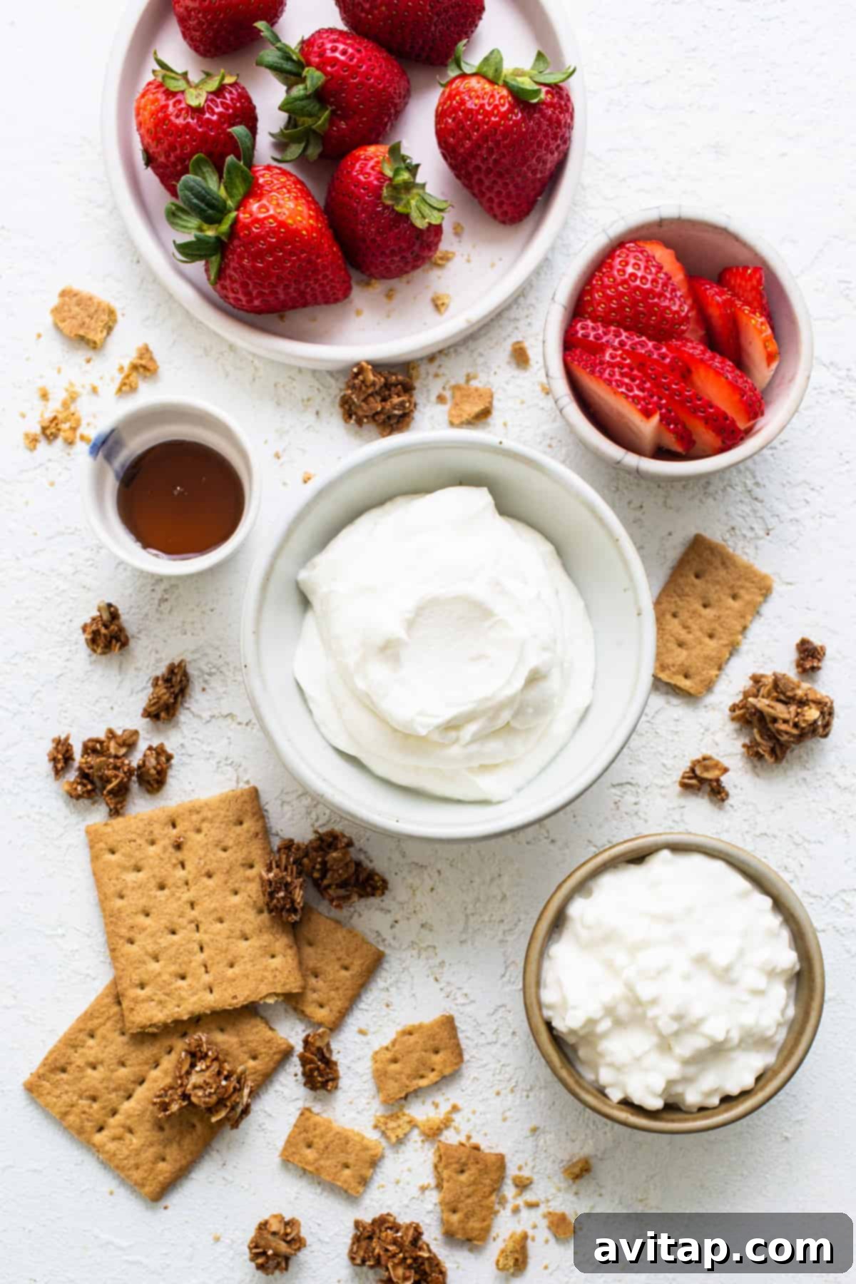 Strawberries, graham crackers and whipped cream on a white background.