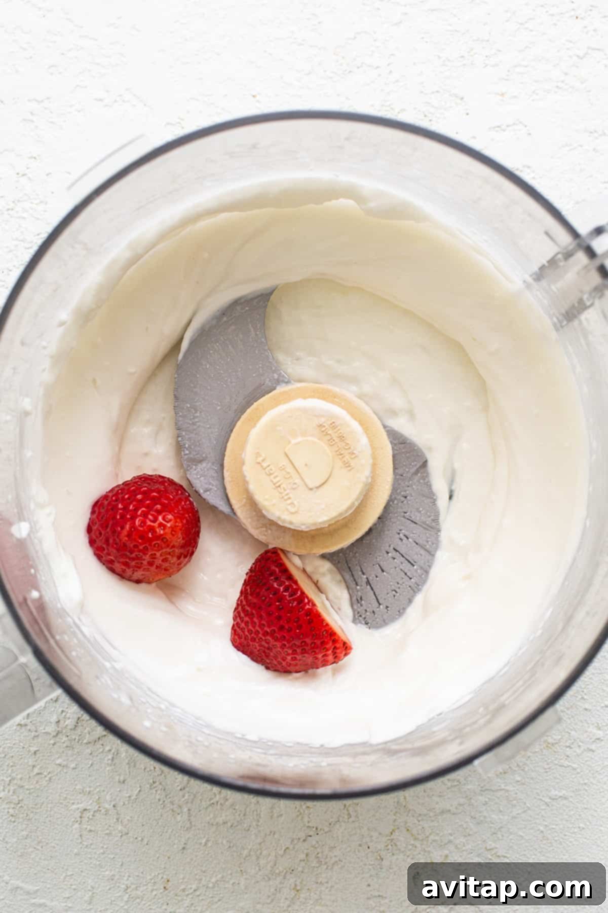 A food processor with whipped cream and strawberries.