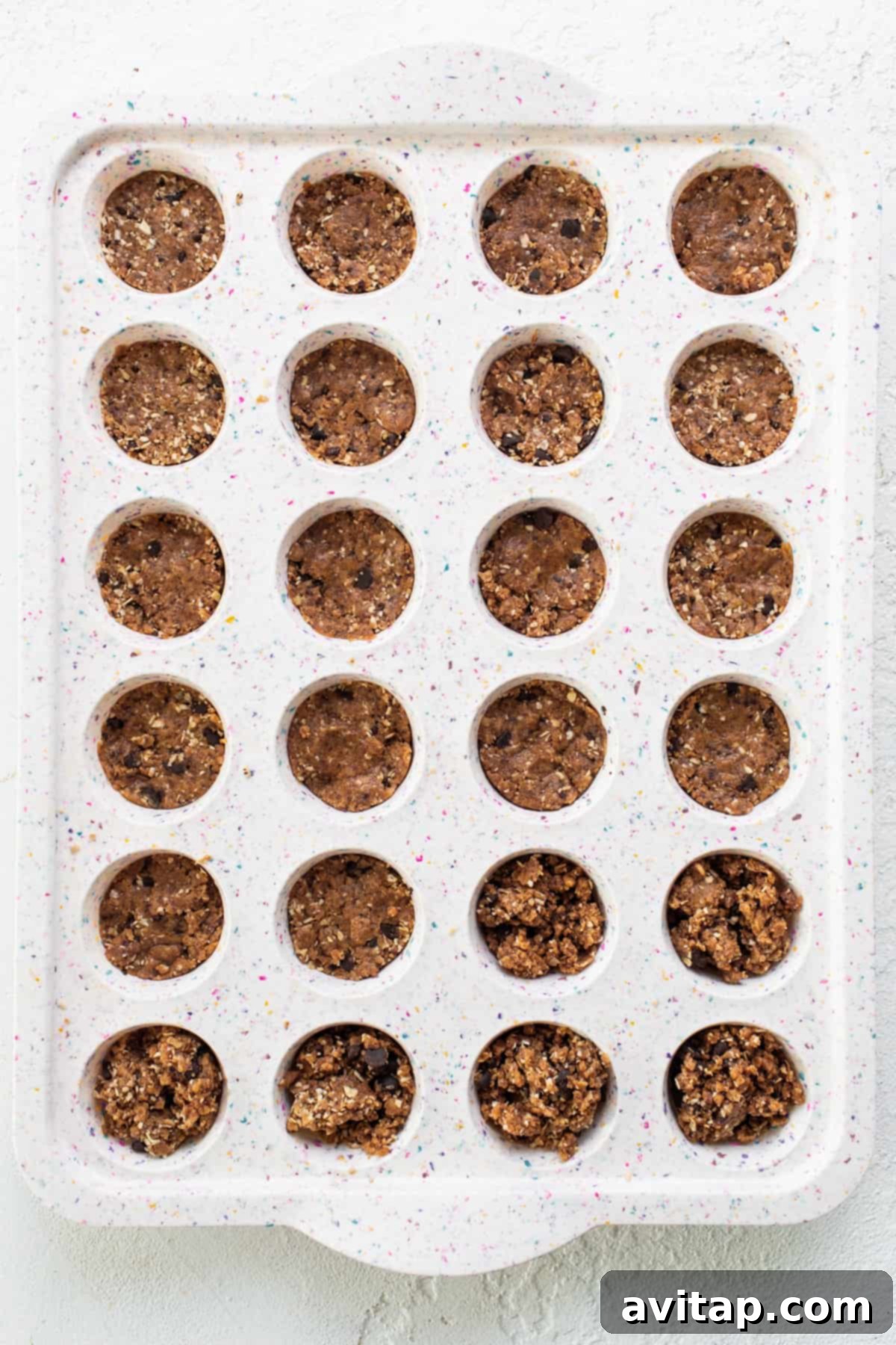 A tray filled with neatly scooped chocolate chip cookie dough portions, ready for shaping into cups.