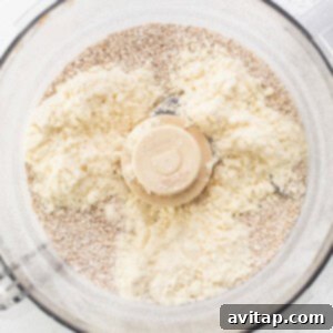 A food processor filled with flour and other ingredients, showing the initial blending stage for the cookie dough base.