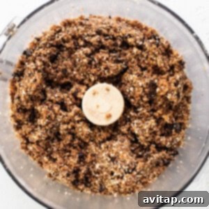 A food processor filled with granola and a banana, indicating the final mixing stage before shaping the cookie dough.