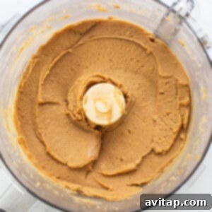 Protein Packed Monster Cookie Dough 9 Peanut butter and other wet ingredients being blended in a food processor to form the smooth base for the cookie dough.