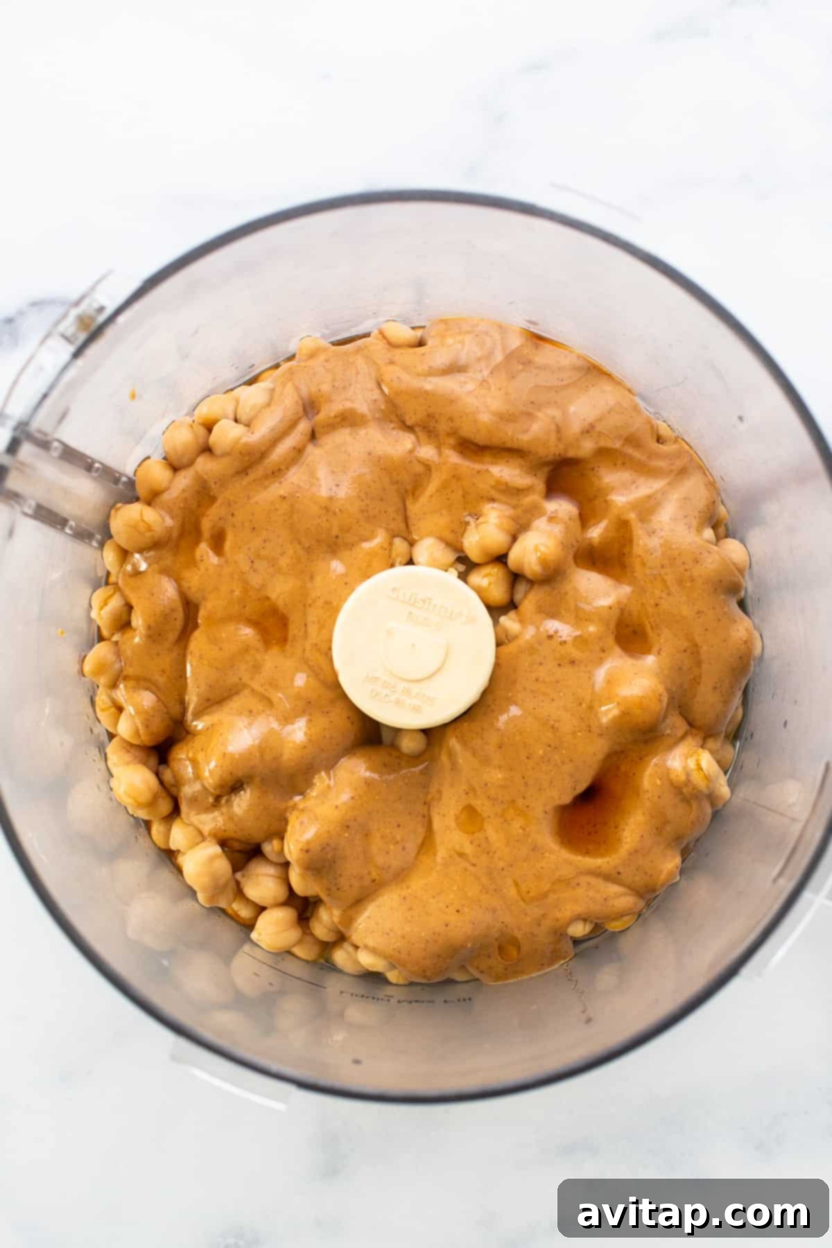 Protein Packed Monster Cookie Dough 3 A high-speed food processor blending creamy, natural peanut butter, which forms a vital part of the protein monster cookie dough base.
