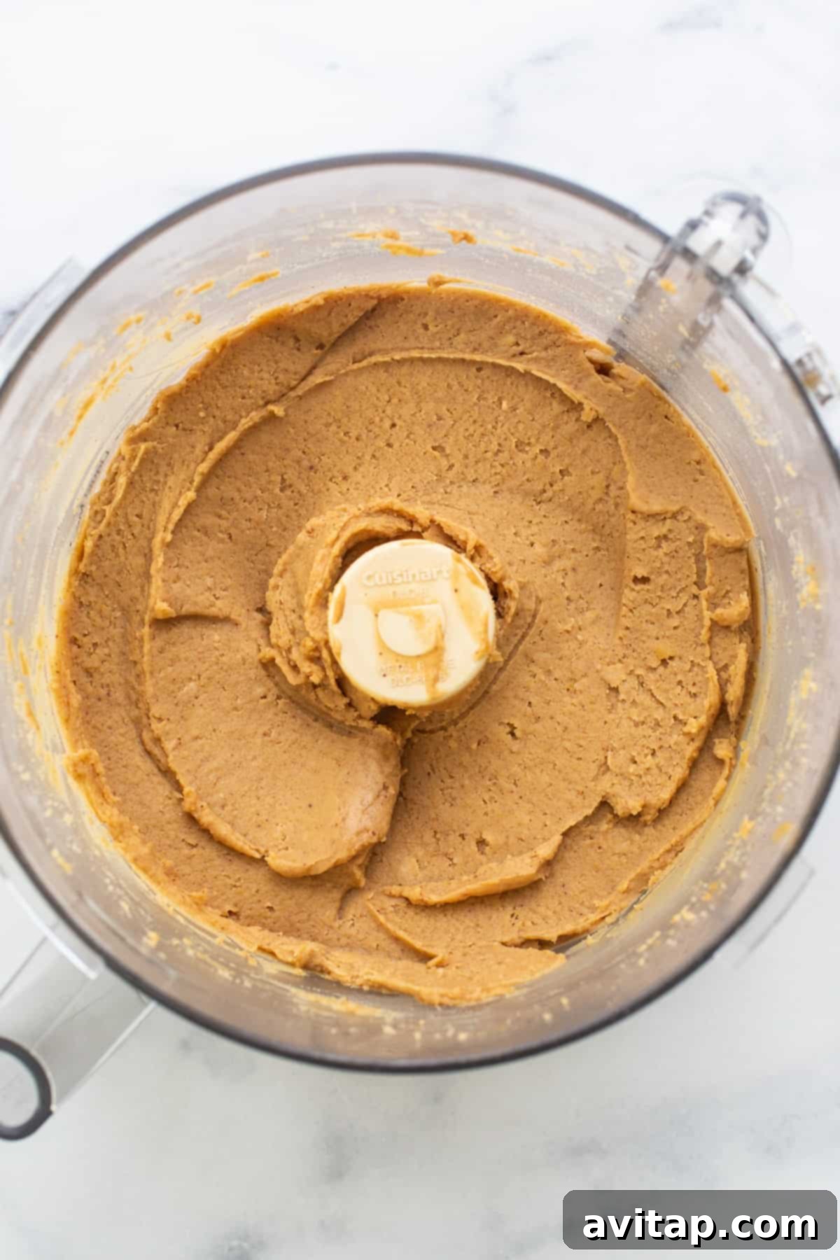 Protein Packed Monster Cookie Dough 4 The blended, smooth base of garbanzo beans, peanut butter, and maple syrup sits in a food processor, perfectly prepared for the final delicious additions.