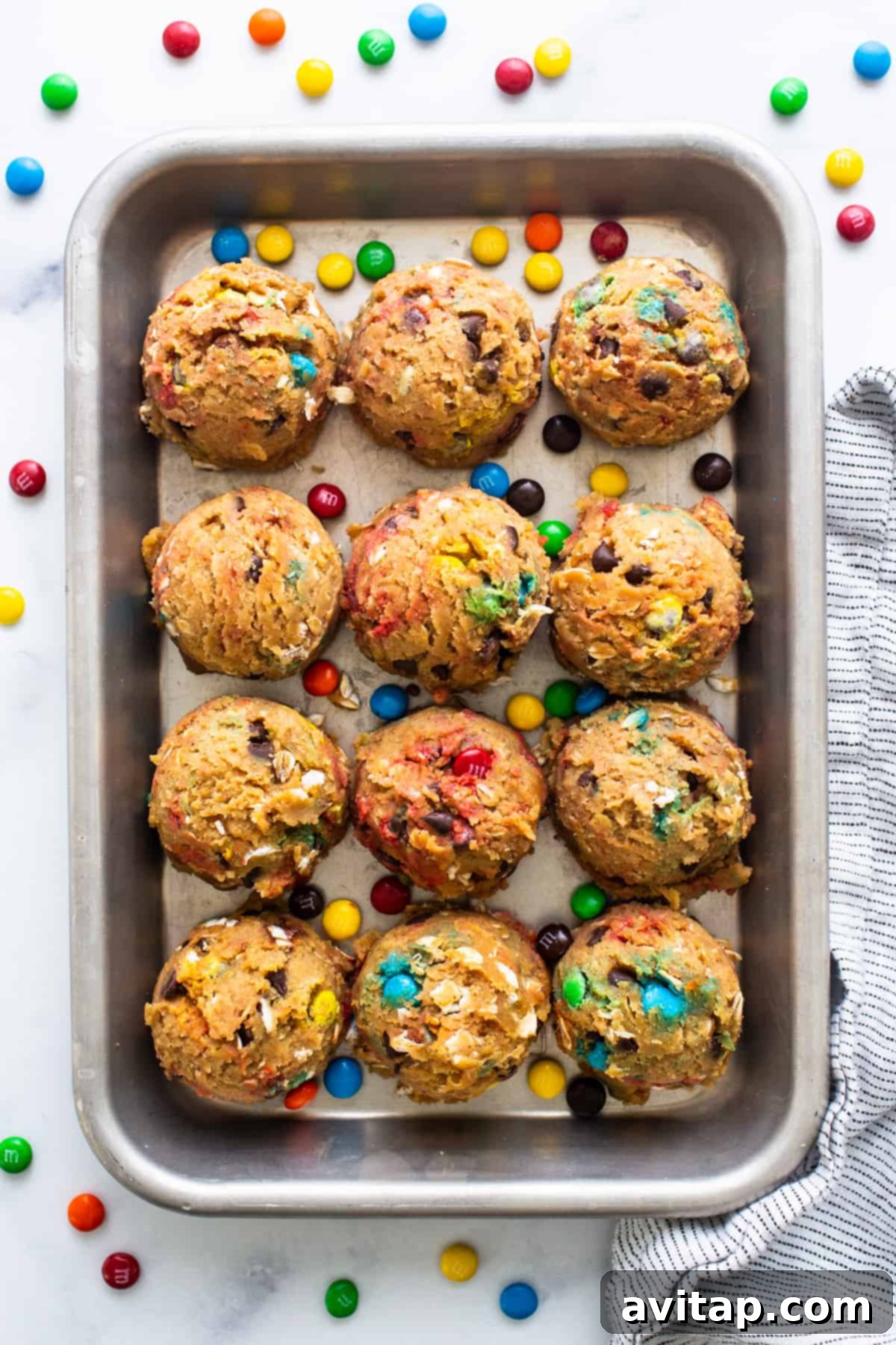 Protein Packed Monster Cookie Dough 6 A baking pan filled with freshly baked monster cookies, featuring an assortment of vibrant M&M's and golden-brown edges, ready to be enjoyed.