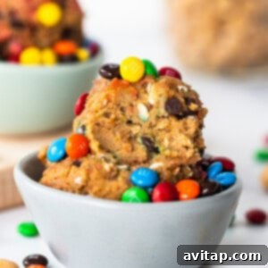 A bowl filled with protein monster cookie dough, featuring mini chocolate chips and M&M's, ready to be served.