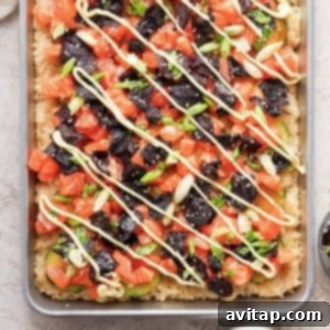 A pizza with salmon, avocado, and arugula on a baking sheet, representing the finished dish.